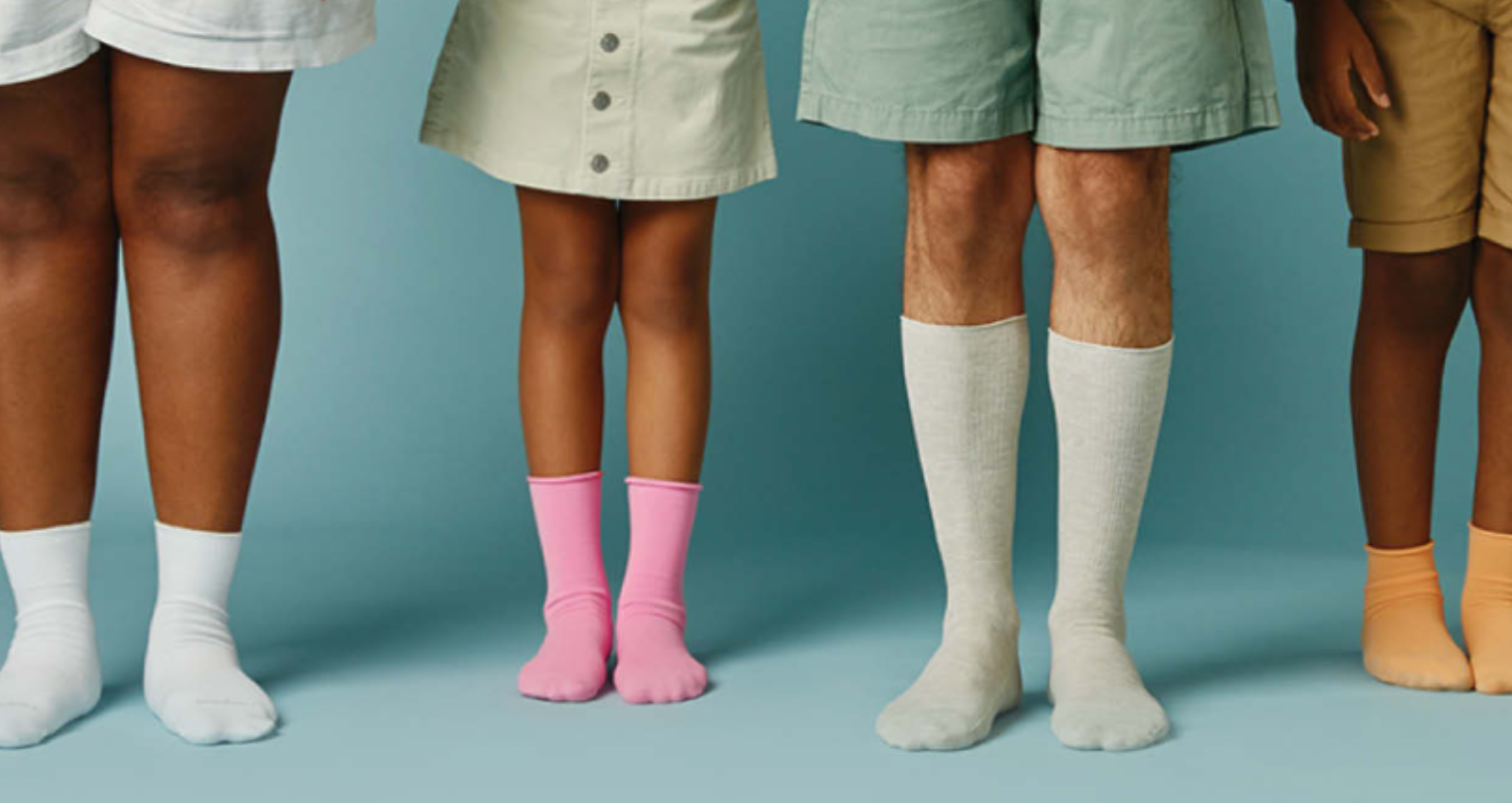 four people standing with just legs showing, wearing socks.