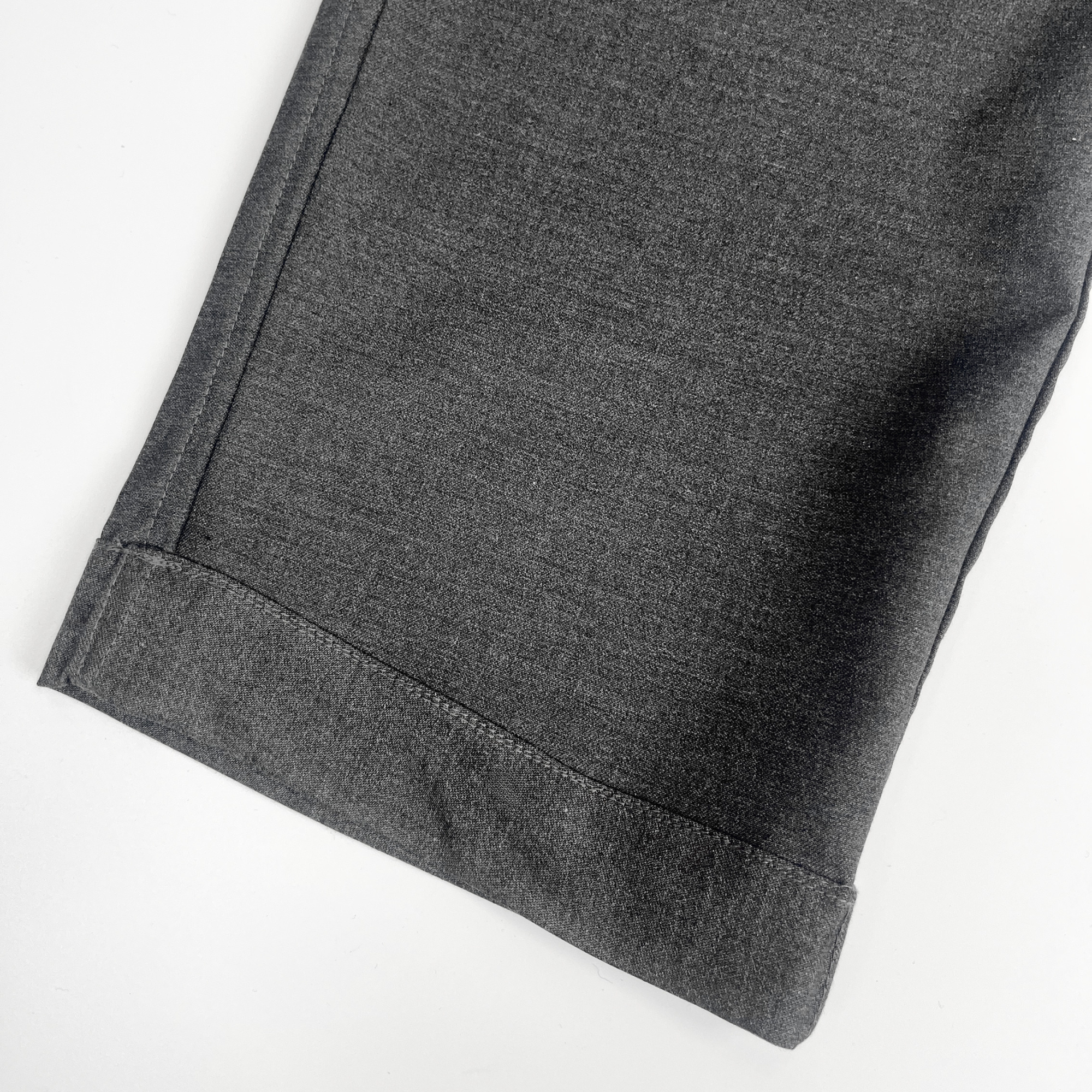 Close-up of charcoal school trouser hem on a white background. Hem is adjustable.