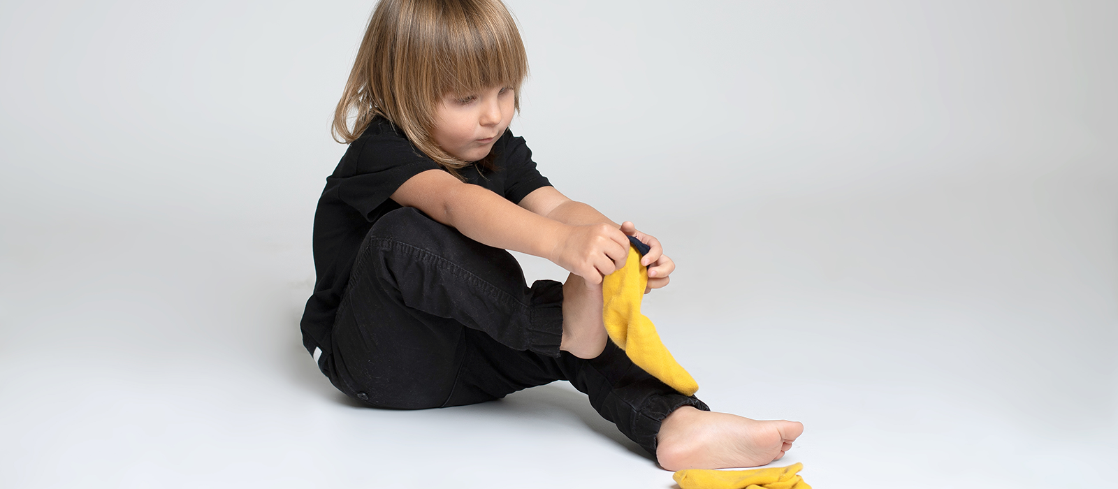 Young girl putting on a pair of yellow socks